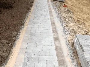 Light gray concrete pavers laid in a walkway over a gravel base, with edge restraints and gravel shoulders on either side