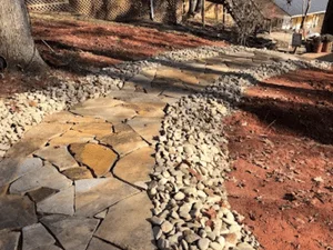 Irregular flagstone walkway edged with rounded river rock beside red mulch beds